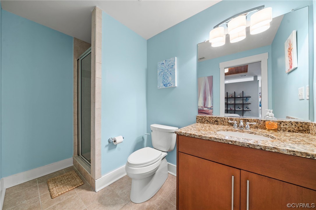 Second of two Bathrooms in primary with tile floors, toilet, vanity, and walk in shower