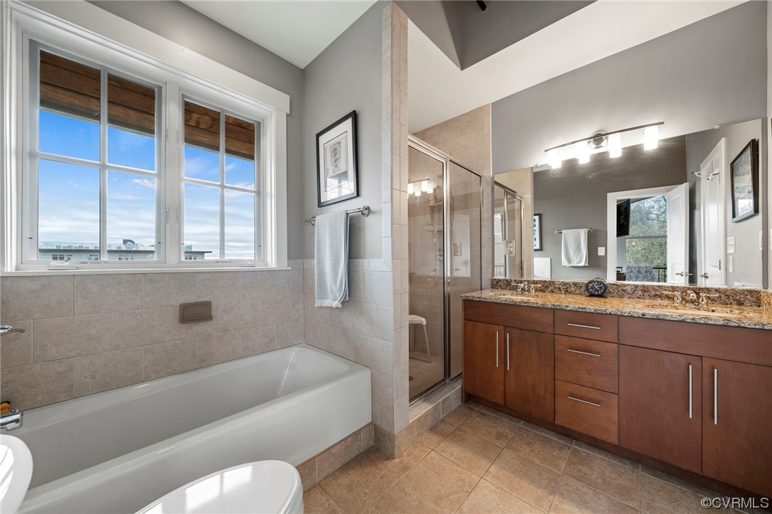Full bathroom featuring dual vanity, toilet, tile flooring, and plus walk in shower