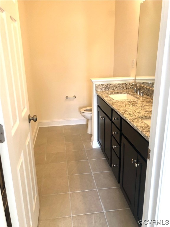Bathroom featuring toilet, double sink vanity, and tile floors