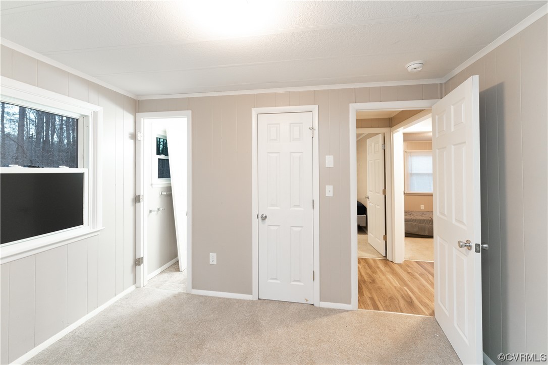 Unfurnished bedroom with light carpet, ornamental molding, and a closet
