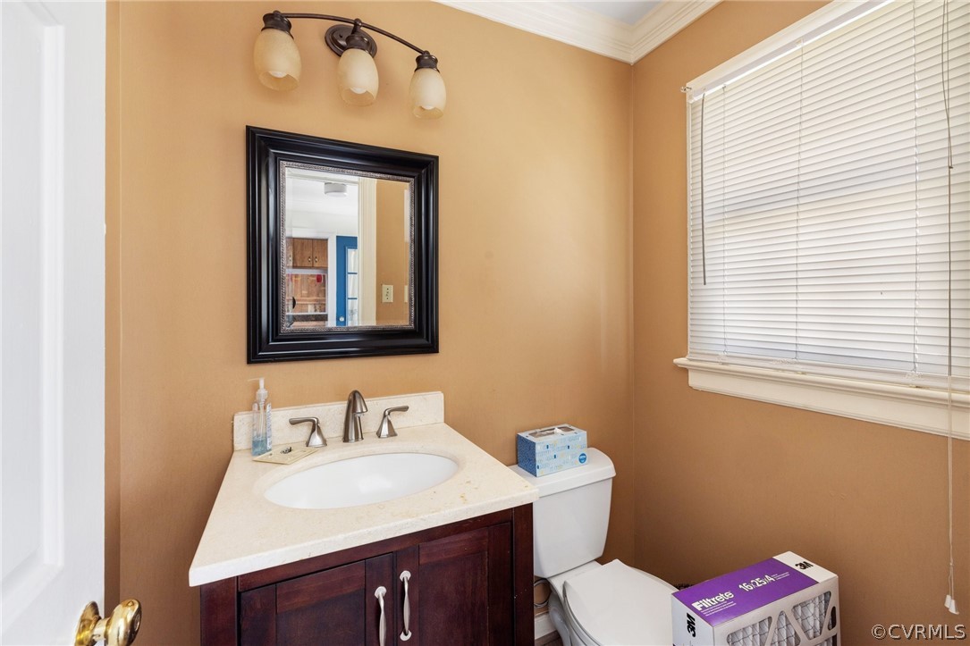 Bathroom featuring crown molding, vanity, and toilet