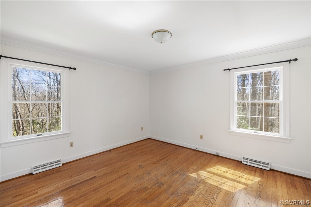 Empty room featuring crown molding and light wood-type flooring