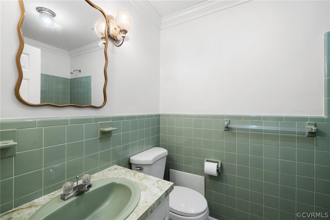 Bathroom with tile walls, backsplash, ornamental molding, oversized vanity, and toilet