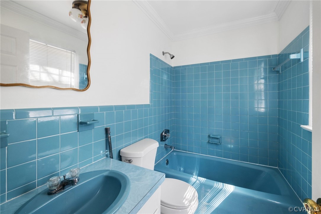 Full bathroom featuring tiled shower / bath, tile walls, and toilet