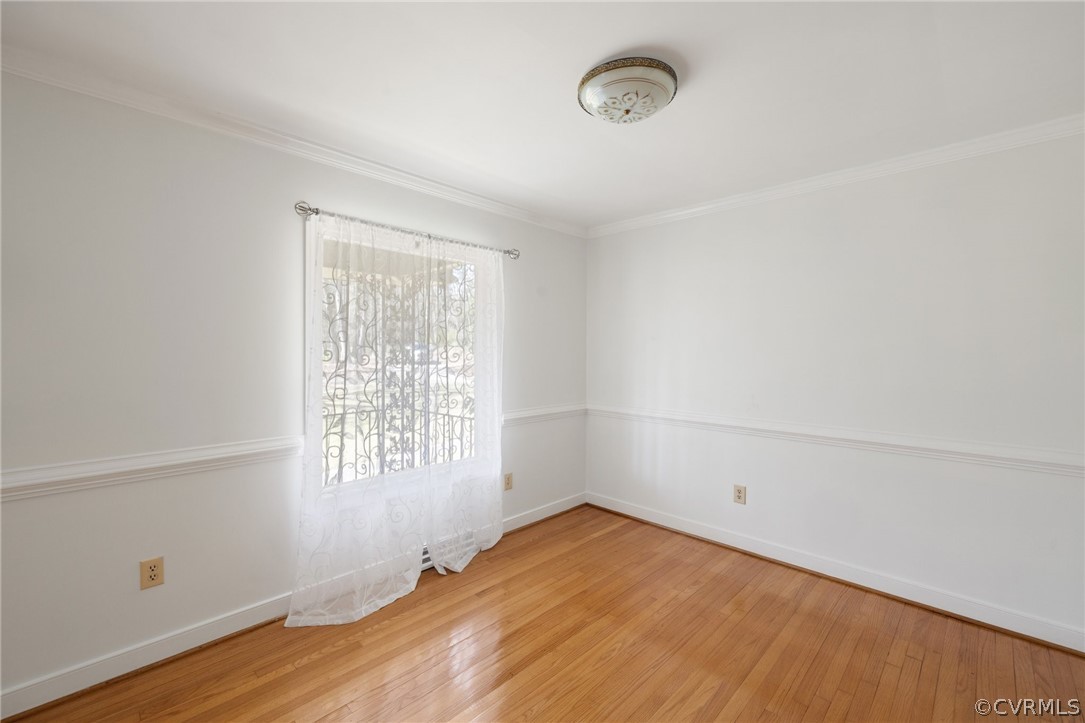 Spare room featuring ornamental molding and light wood-type flooring