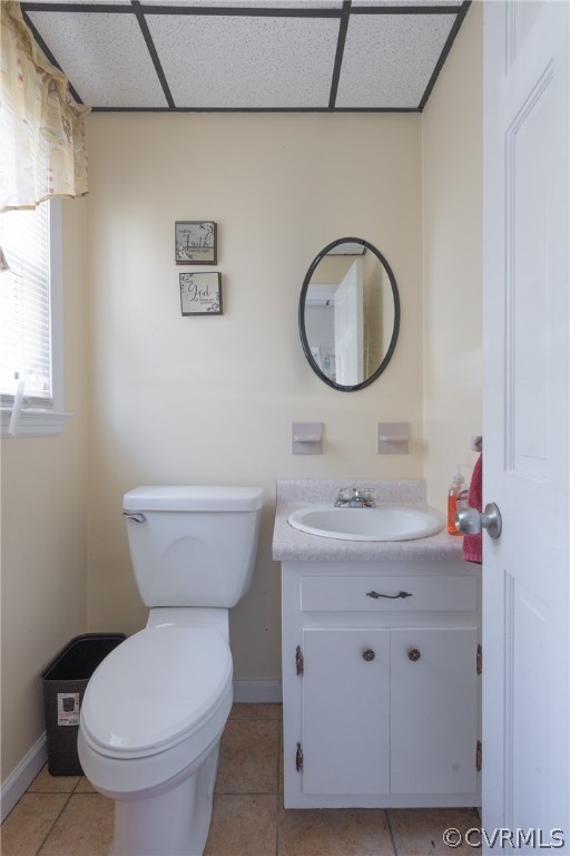Bathroom featuring vanity, toilet, tile floors, and a drop ceiling
