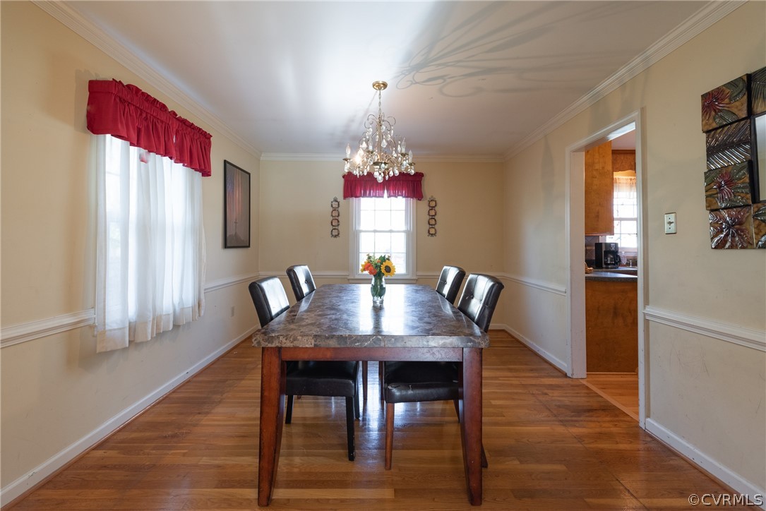 Dining room featuring a notable chandelier, dark hardwood / wood-style floors, and ornamental molding