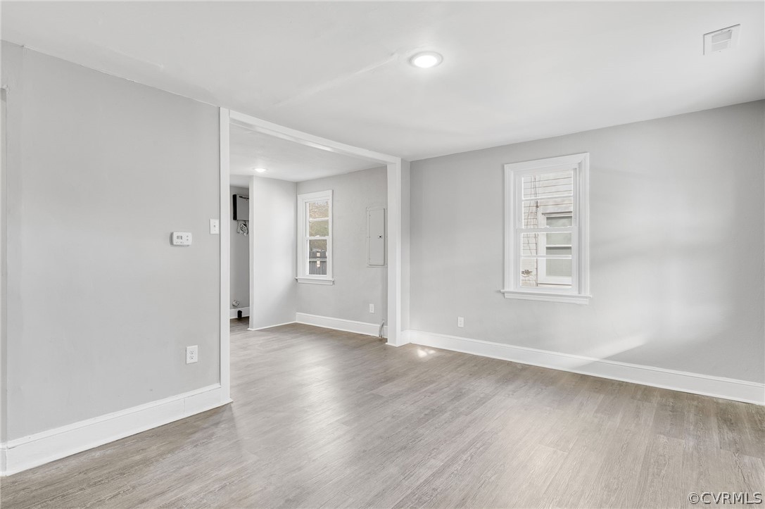Empty room with hardwood / wood-style flooring and plenty of natural light