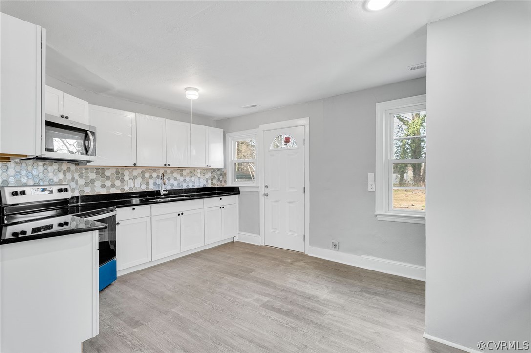 Kitchen with backsplash, electric stove, white cabinets, sink, and light hardwood / wood-style flooring