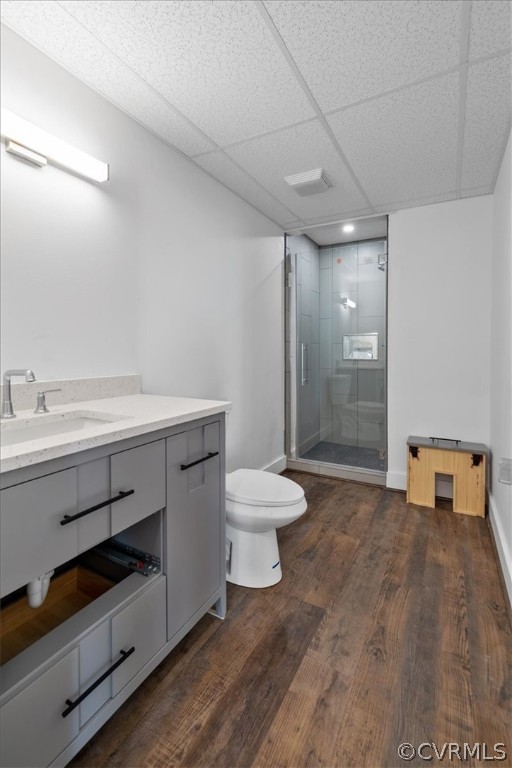 Bathroom featuring hardwood / wood-style floors, a paneled ceiling, toilet, an enclosed shower, and vanity