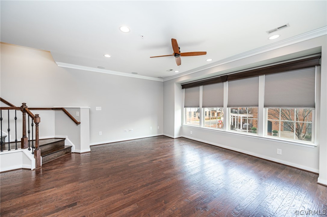 Empty room with ornamental molding, dark hardwood / wood-style flooring, and ceiling fan