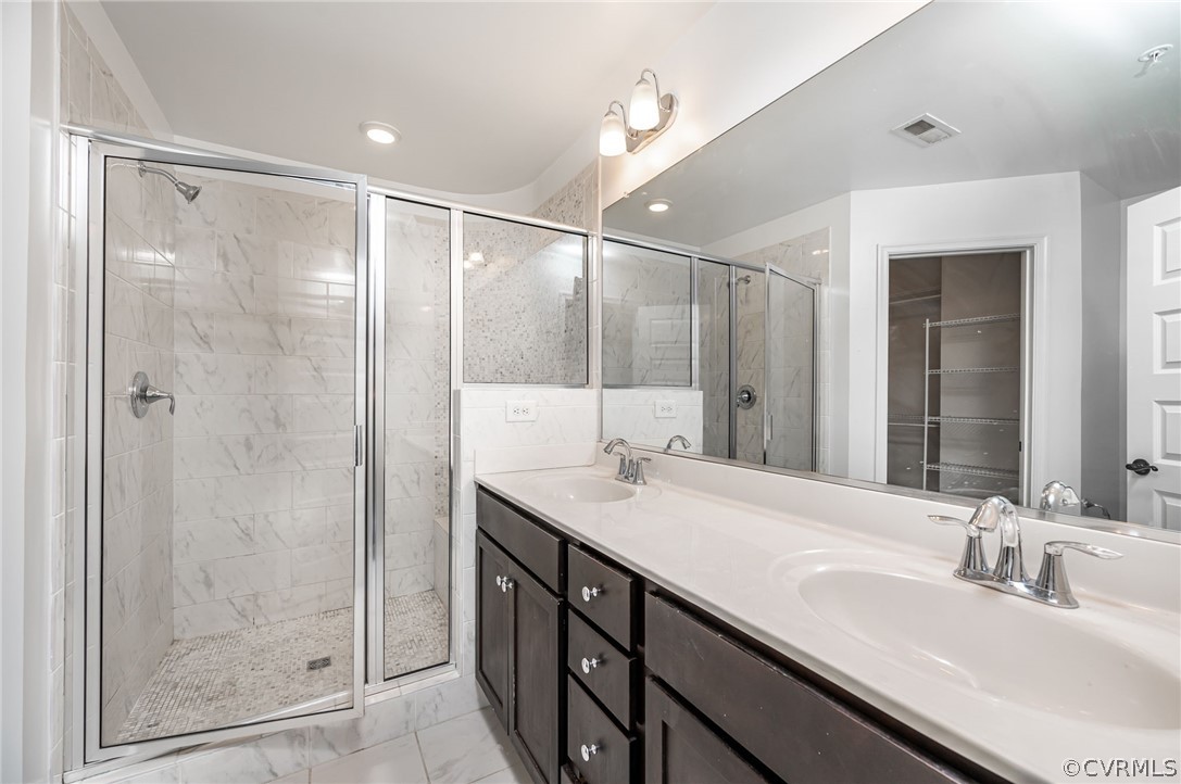 Bathroom featuring dual sinks, tile flooring, a shower with shower door, and large vanity