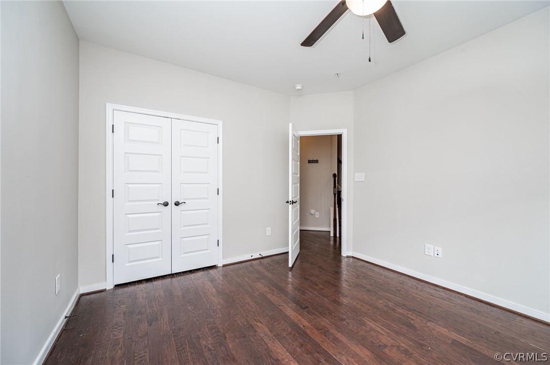 Unfurnished bedroom with dark hardwood / wood-style flooring, a closet, and ceiling fan