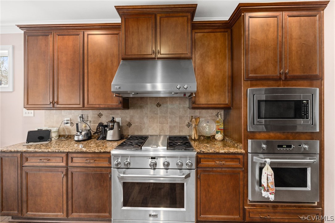 Kitchen with stone countertops, stainless steel appliances, and backsplash