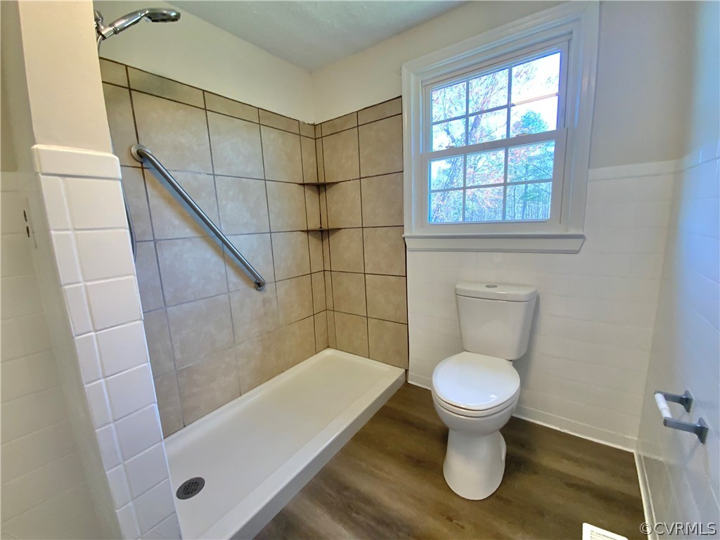 Bathroom with a tile shower, toilet, and hardwood / wood-style floors
