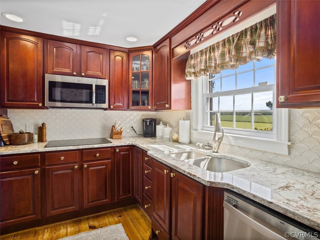 Kitchen featuring sink, dark hardwood / wood-style flooring, backsplash, stainless steel appliances, and light stone counters