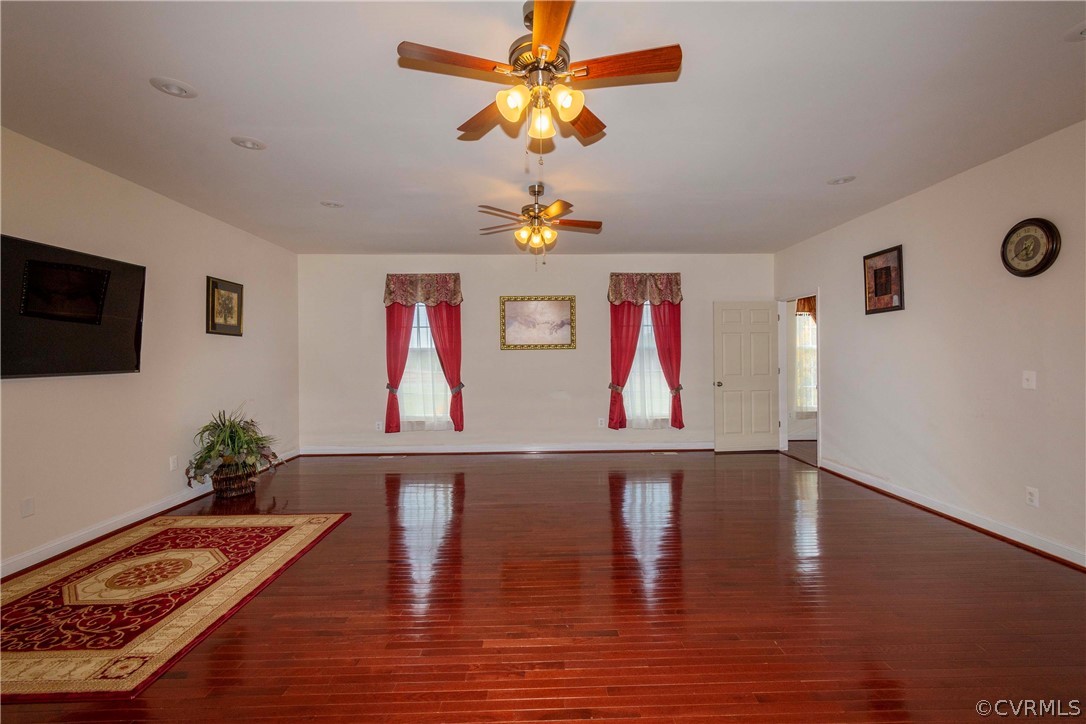 Empty room featuring dark hardwood / wood-style floors and ceiling fan