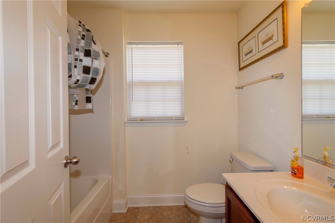 Full bathroom with vanity, toilet, plenty of natural light, and tile floors