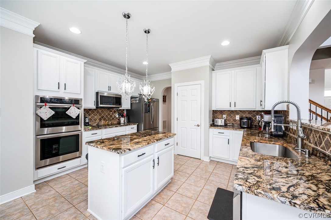 Kitchen with white cabinets, appliances with stainless steel finishes, and backsplash