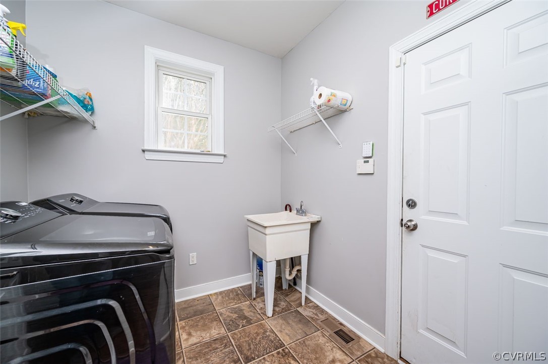 Laundry room featuring washing machine and dryer and dark tile flooring