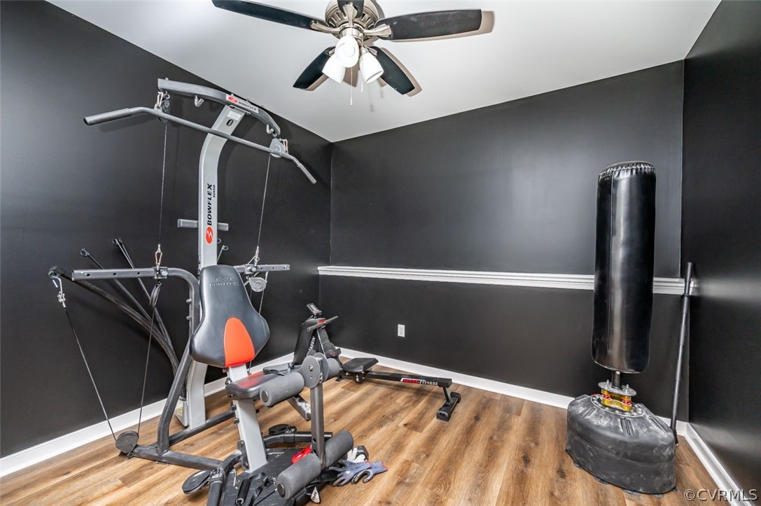 Exercise room with light wood-type flooring and ceiling fan