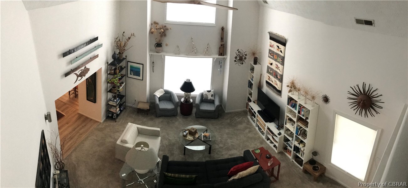 Living room featuring dark colored carpet and ceiling fan