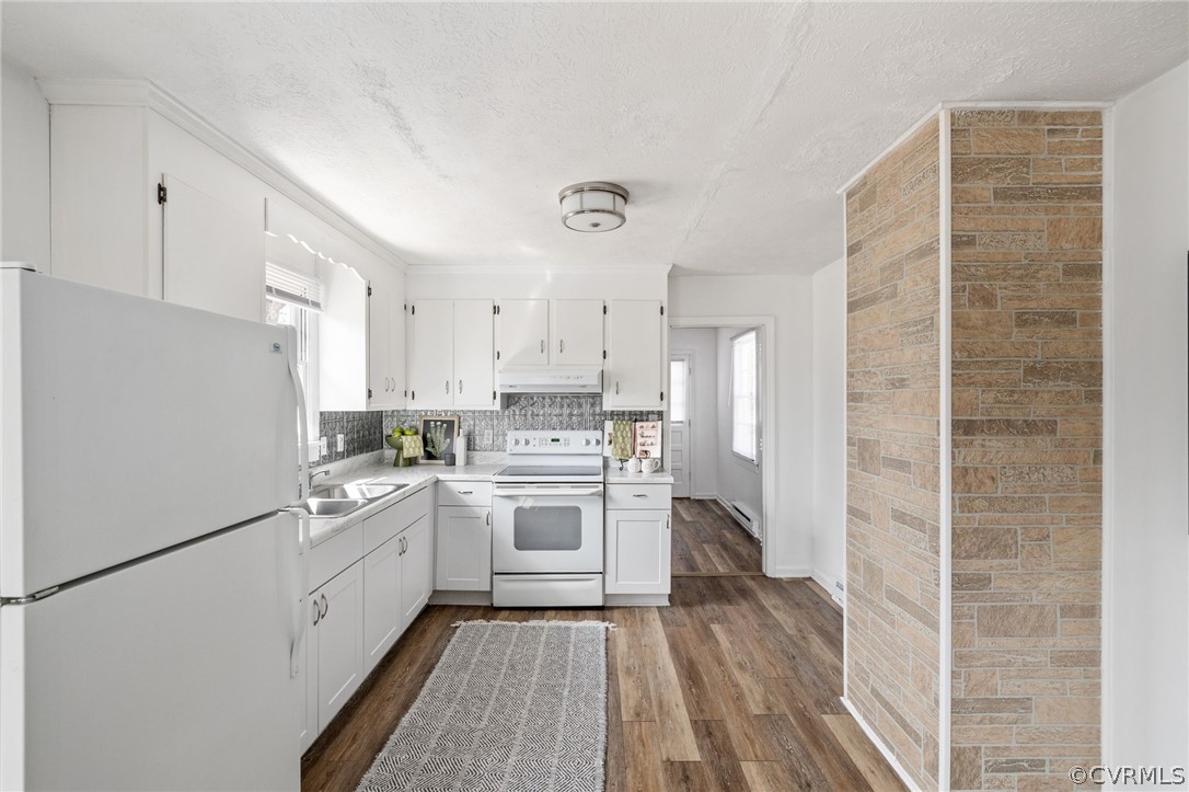 Kitchen featuring dark hardwood / wood-style floors, white appliances, sink, white cabinetry, and tasteful backsplash