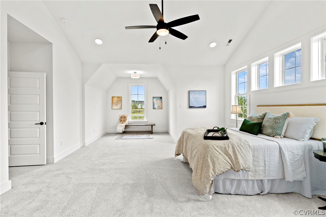 Carpeted bedroom with ceiling fan and vaulted ceiling and sitting area