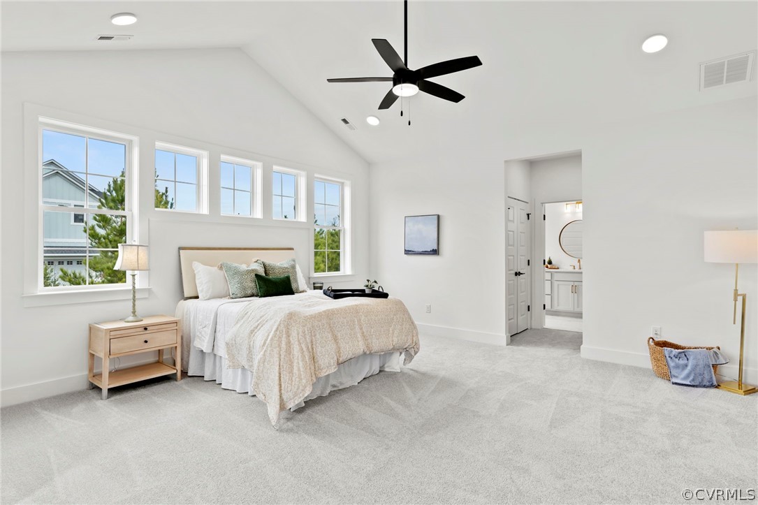 Bedroom with connected bathroom, light carpet, high vaulted ceiling, and ceiling fan