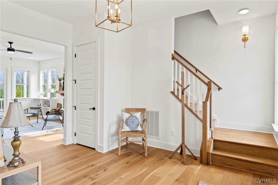 Staircase featuring light hardwood flooring and ceiling fan with notable chandelier.