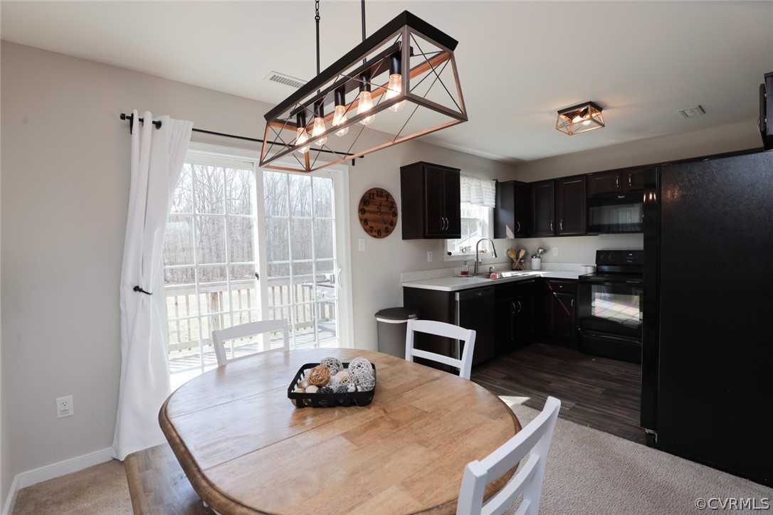 Dining area featuring an inviting chandelier, dark vinyl flooring, and a healthy amount of sunlight