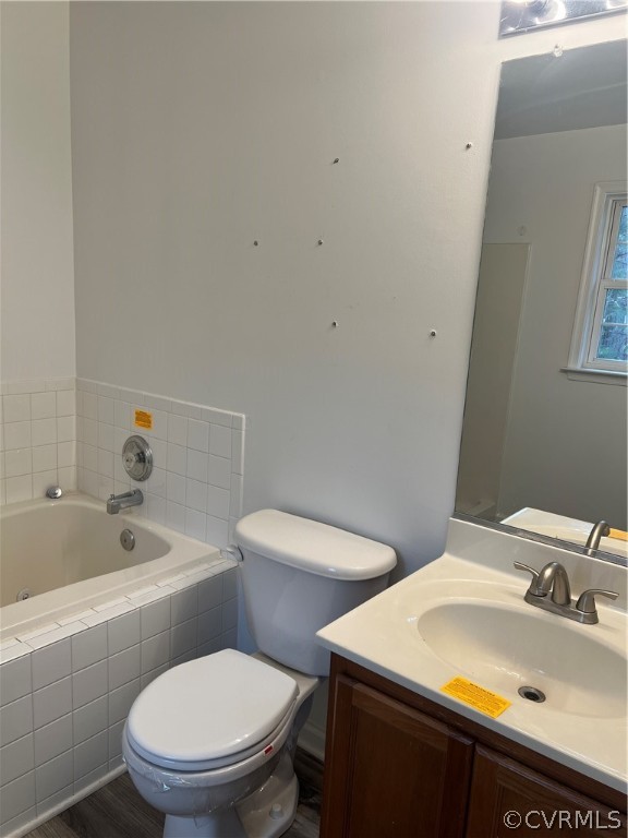Bathroom featuring toilet, tiled bath, hardwood / wood-style flooring, and oversized vanity