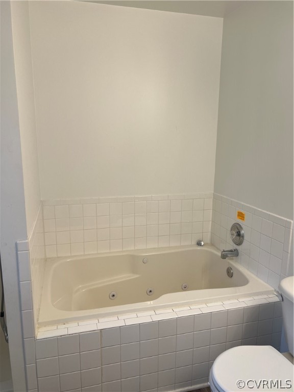 Bathroom featuring tiled bath and toilet