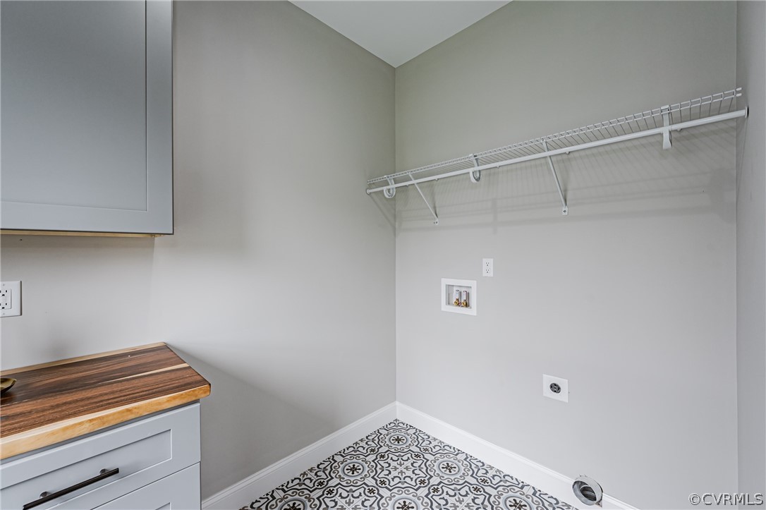 Washroom featuring washer hookup, hookup for an electric dryer, light tile floors, and cabinets