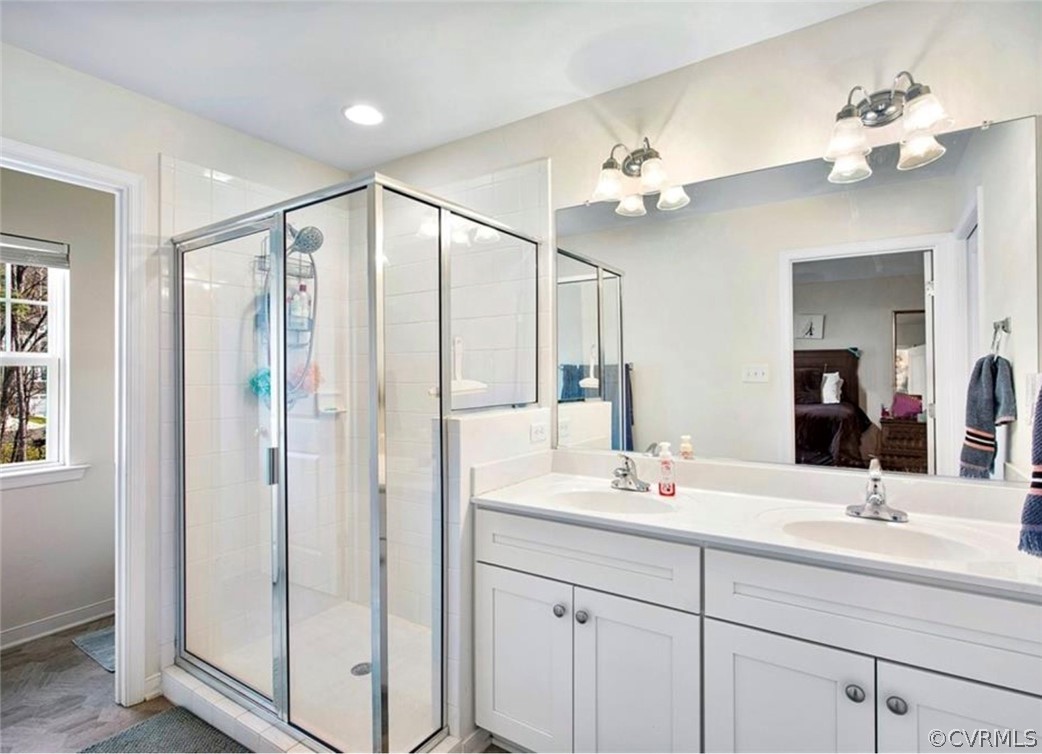 Bathroom with double sink, large vanity, and an enclosed shower