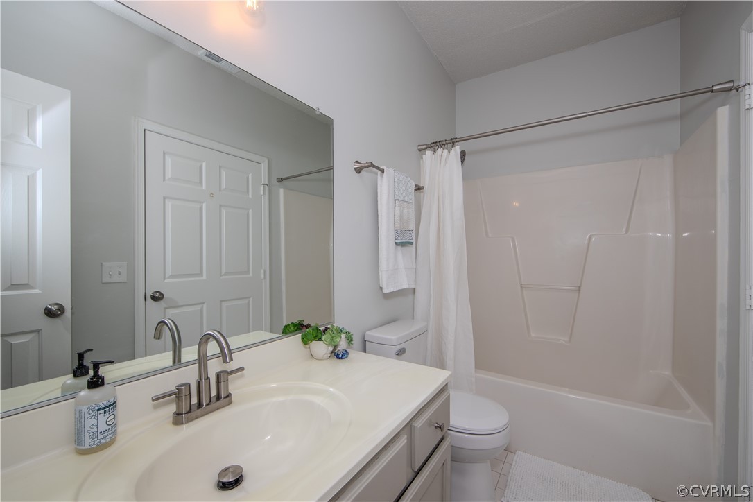 Full bathroom featuring tile flooring, vanity, shower / bath combination with curtain, and toilet