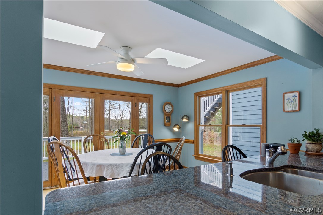 Dining room featuring a skylight, crown molding, ceiling fan, and sink