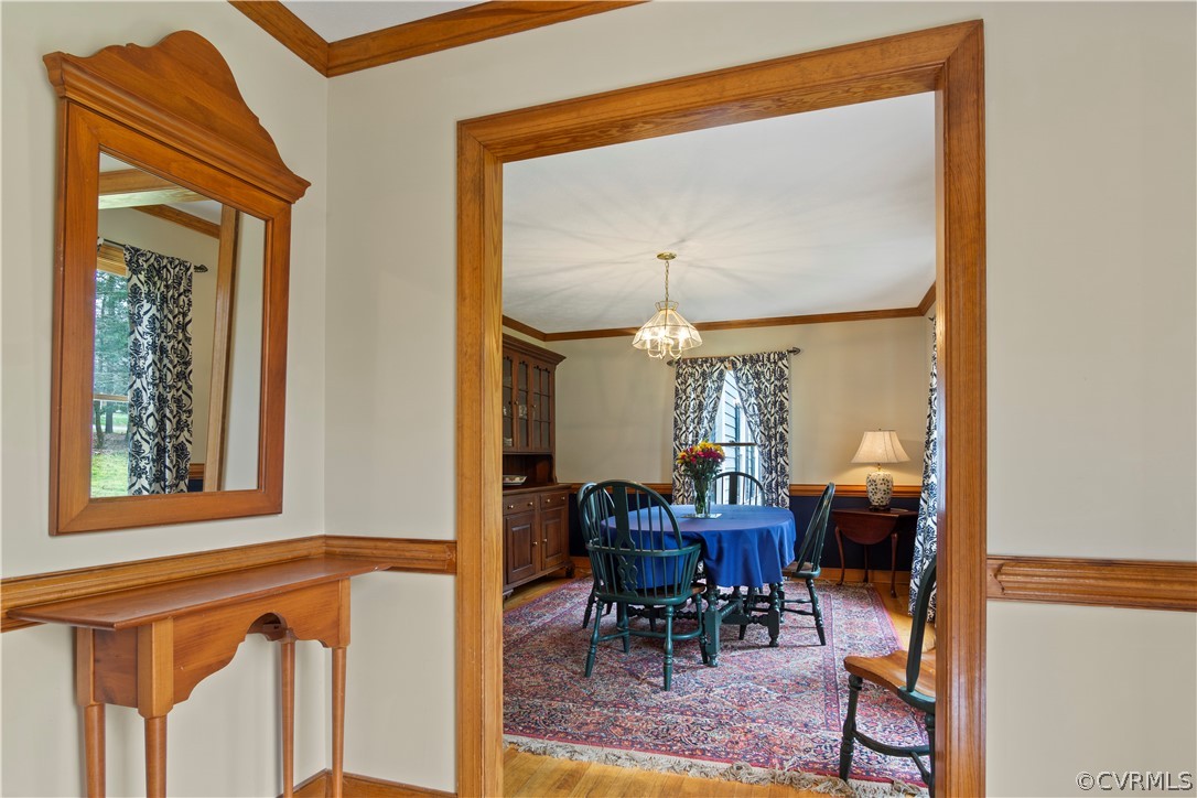 Dining area with crown molding, a chandelier, and hardwood / wood-style flooring