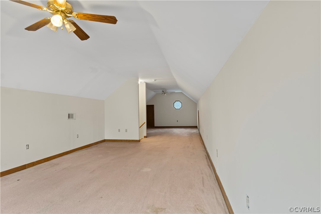 Additional living space featuring light carpet, lofted ceiling, and ceiling fan