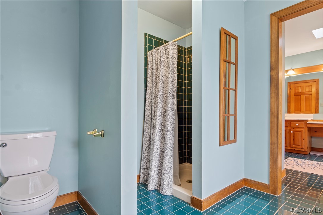 Bathroom with vanity, curtained shower, tile floors, and toilet