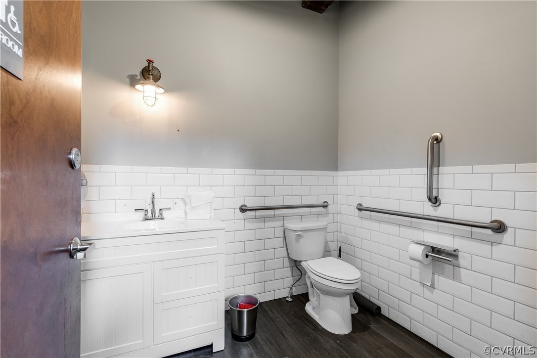 Bathroom featuring vanity, wood-type flooring, tile walls, and toilet
