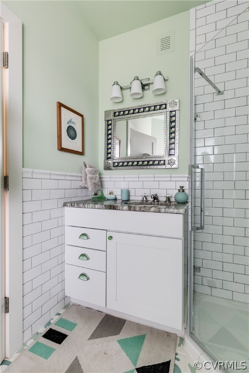 Bathroom featuring walk in shower, tile floors, large vanity, and tile walls