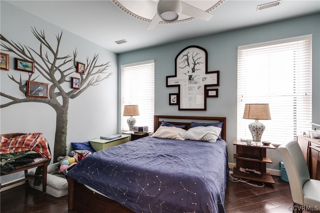 Bedroom with multiple windows, dark hardwood / wood-style flooring, and ceiling fan