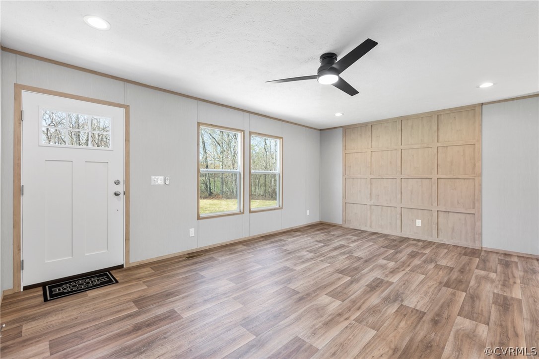 Foyer entrance with ceiling fan and light hardwood / wood-style flooring