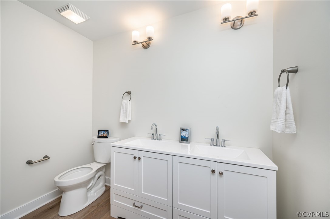 Bathroom featuring LVP hardwood / wood-style floors, double vanity, and toilet