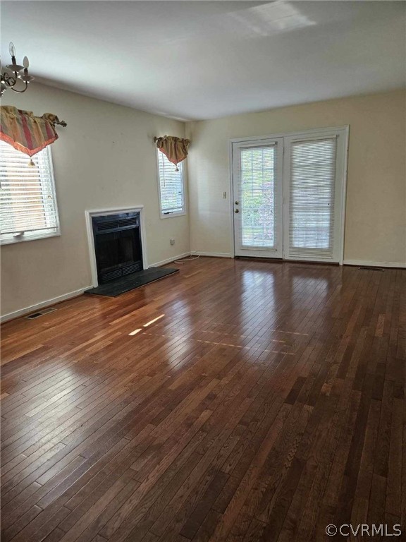 Unfurnished living room featuring dark hardwood / wood-style flooring and a notable chandelier