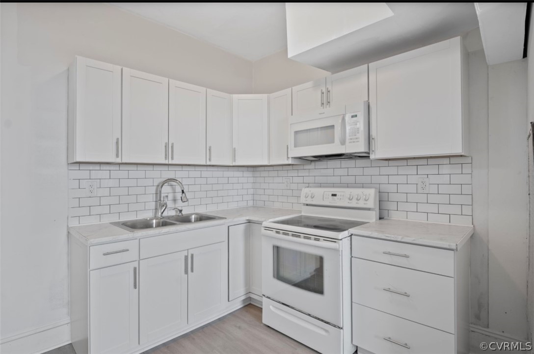Kitchen with backsplash, white cabinets, white appliances, and light hardwood / wood-style floors