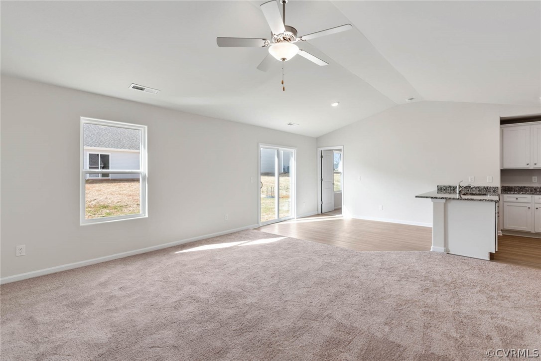 Unfurnished room with lofted ceiling, light colored carpet, and ceiling fan