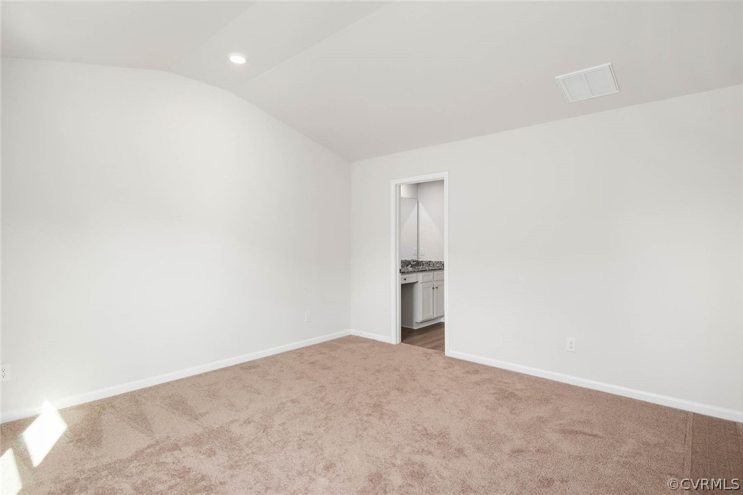 Empty room featuring vaulted ceiling and carpet floors