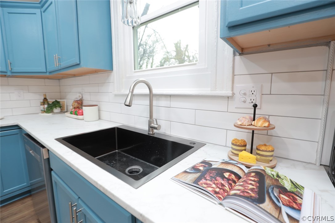 Kitchen featuring blue cabinetry, backsplash, and sink